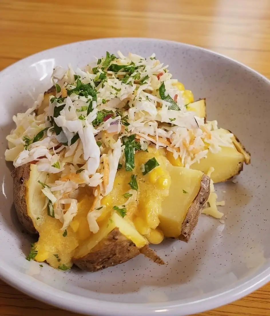 Delicious baked potato topped with fresh vegetables, cheese, and herbs